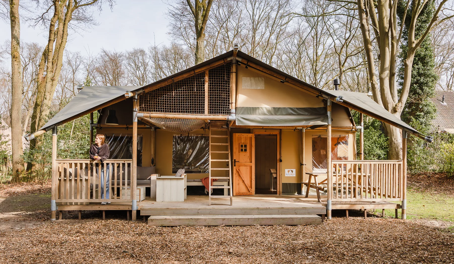 Veranda van een glamping tent op Gooise Heide met gast aan de reling