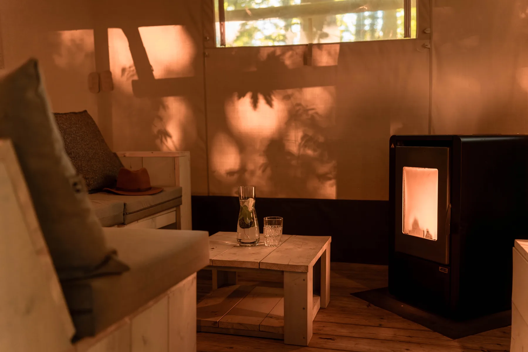 Sfeervolle zithoek met houtkachel in een glamping tent