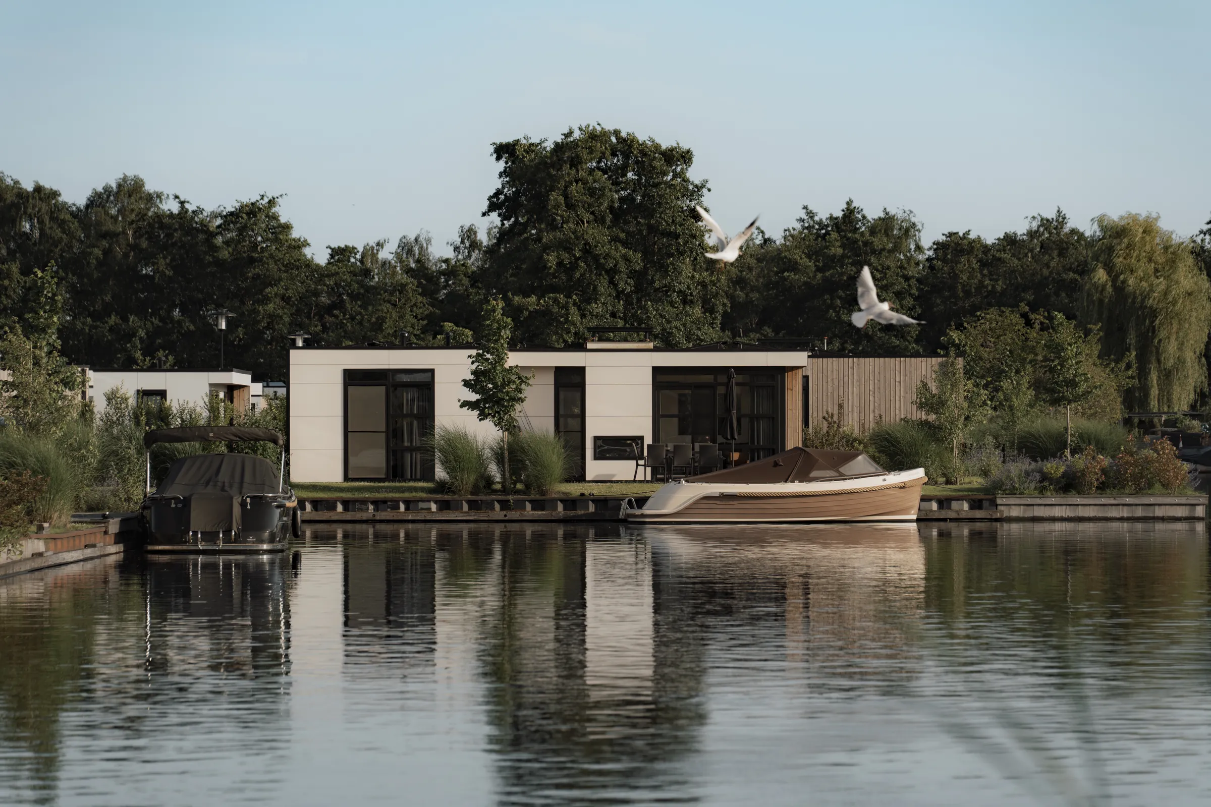 Vakantiewoning aan het water op MarinaPark Nieuw Loosdrecht met sloepen aan de steiger en overvliegende meeuwen