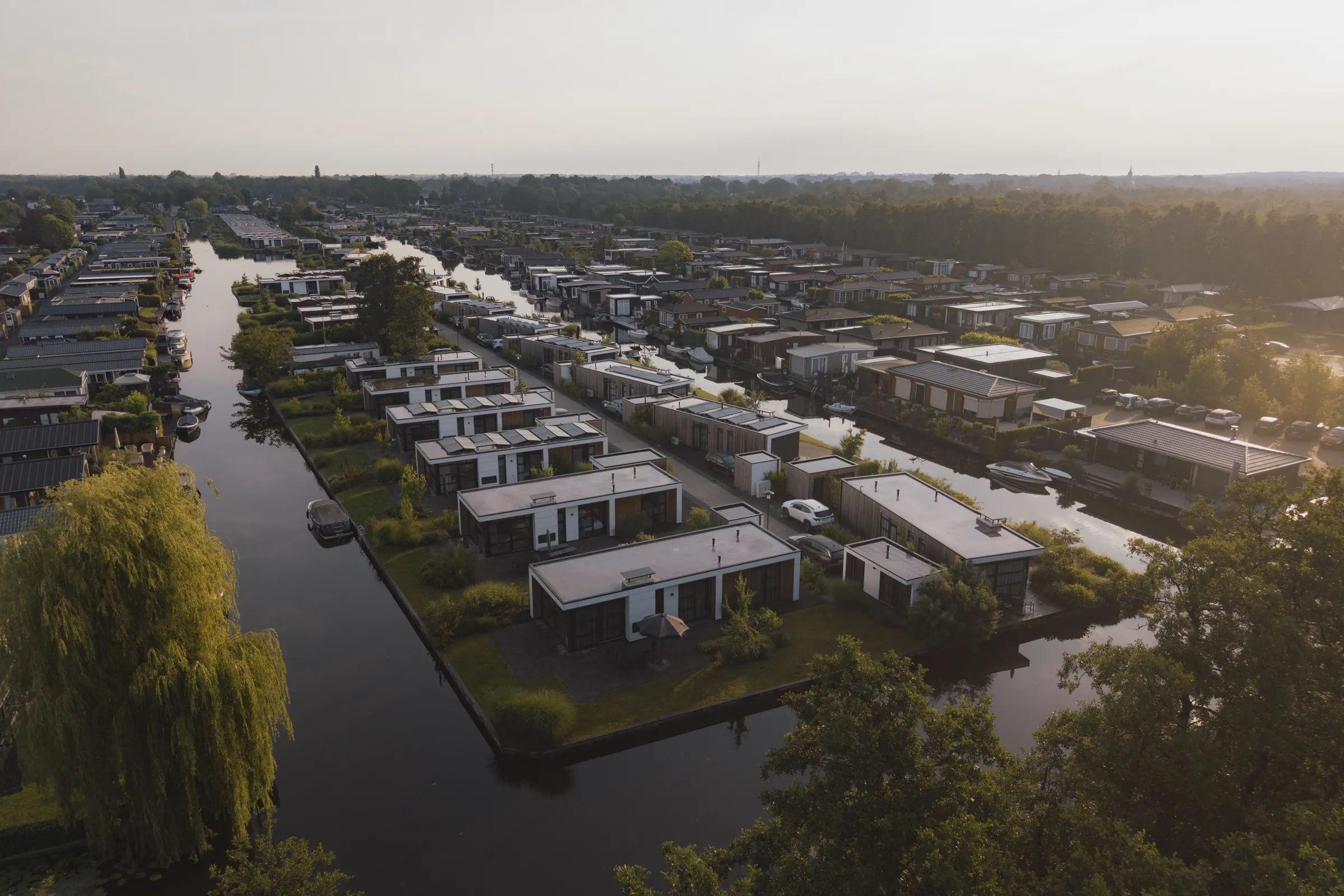 Luchtfoto van de vakantiewoningen van MarinaPark Nieuw Loosdrecht langs het water in het avondlicht