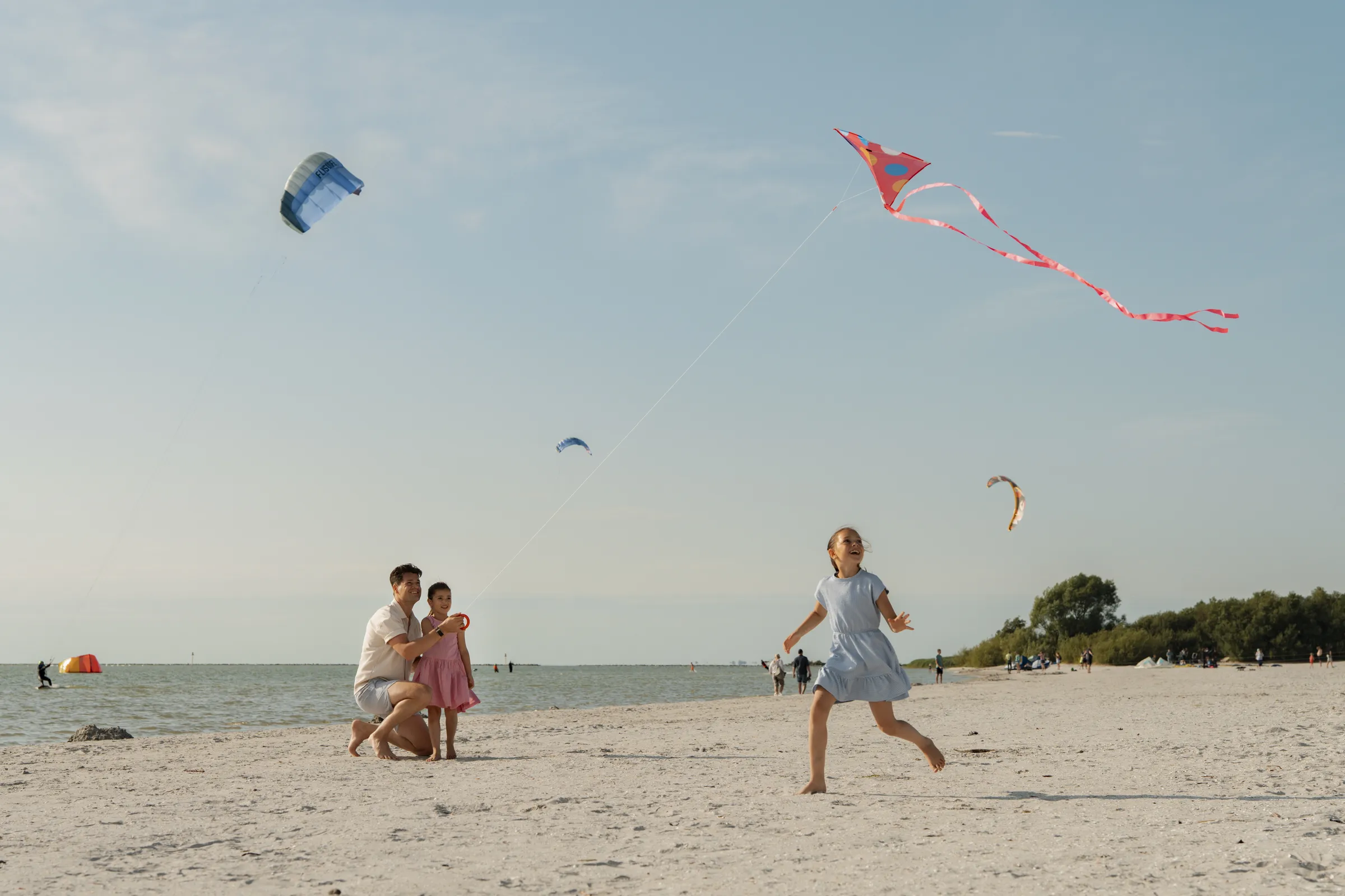Vader en twee kinderen vliegeren op het strand van MarinaPark Soal aan het IJsselmeer