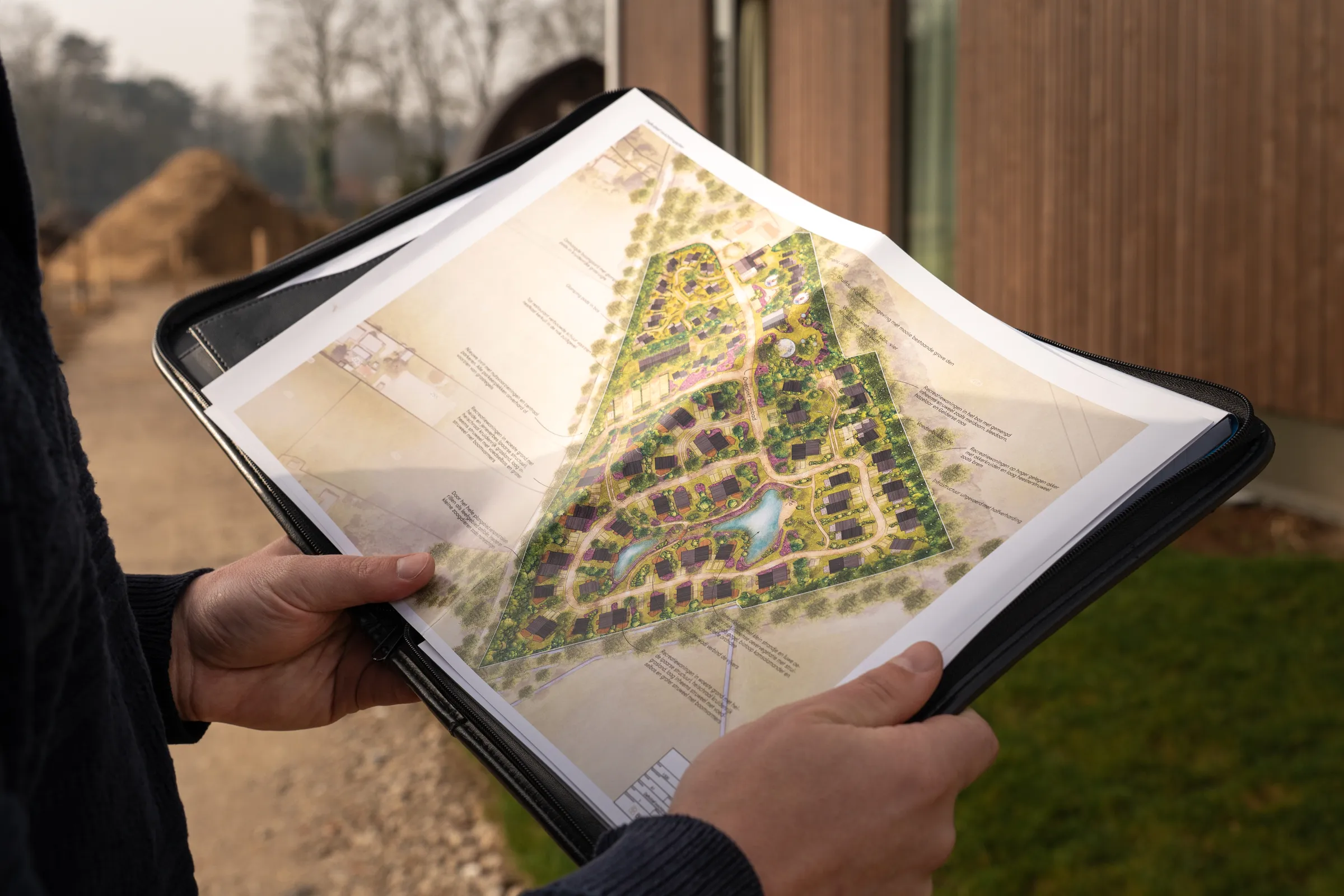 Handen houden de ingekleurde plattegrond van Nala Village vast tijdens het open huis