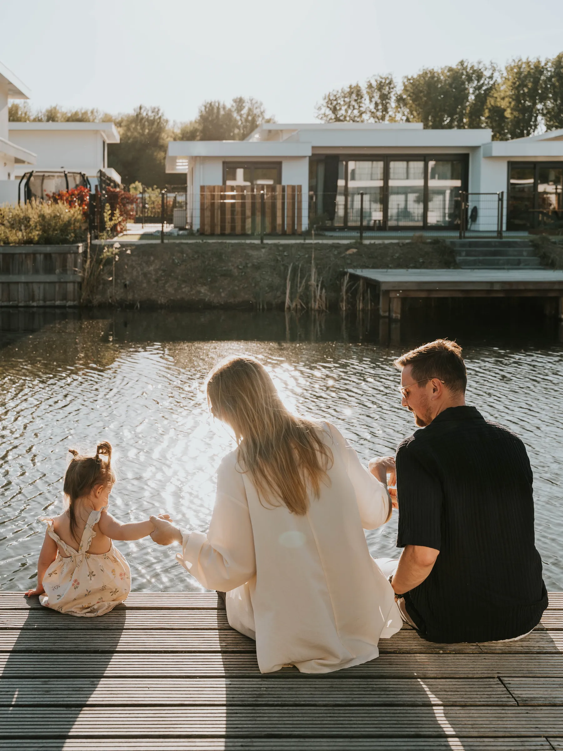 Gezin op een steiger aan het water, met vakantiewoningen aan de overkant