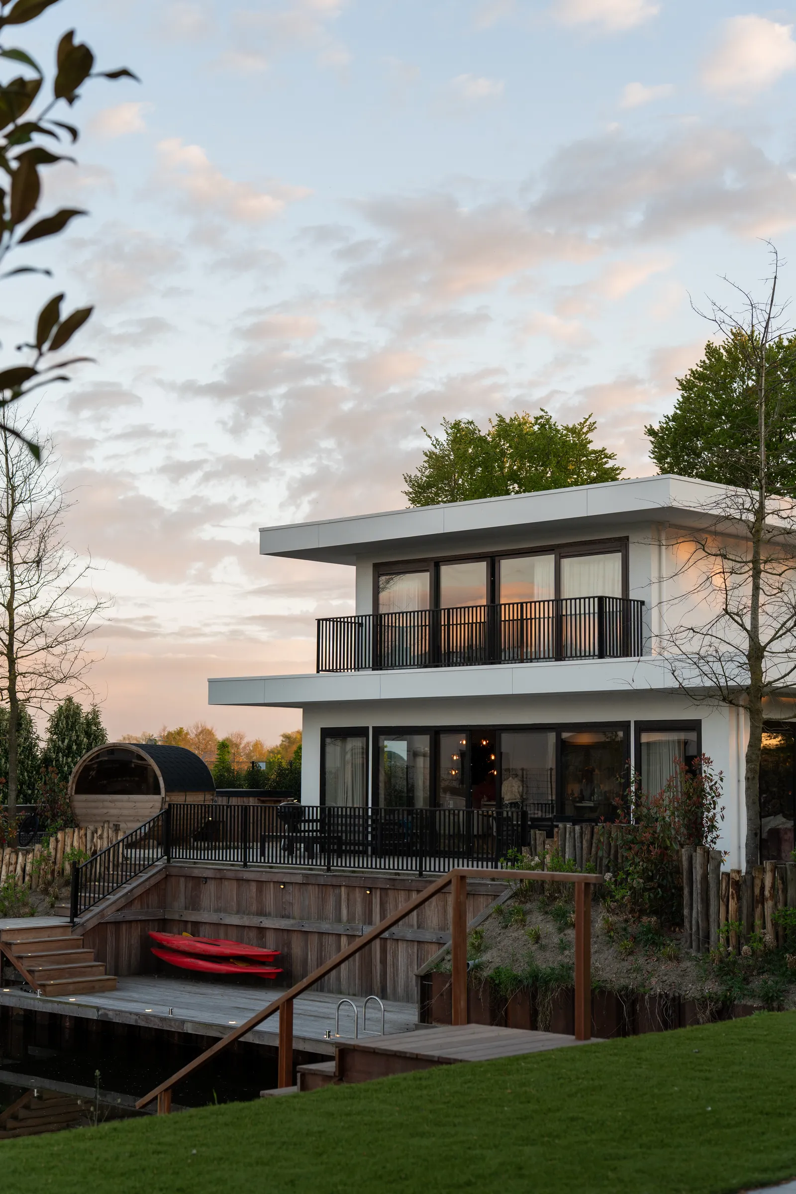 Witte watervilla met terras en steiger bij zonsondergang op Harderwold